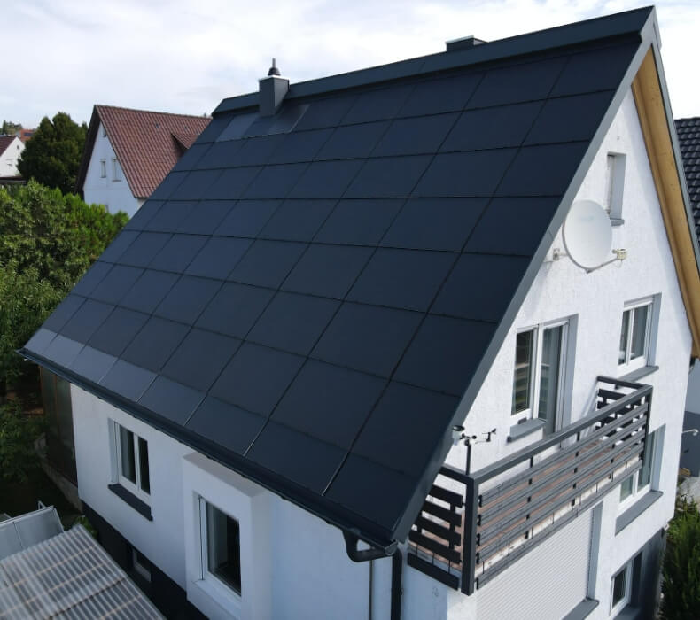 Photovoltaik - Ein weißes Haus mit saniertem Dach mit In-Dach PV-Modulen