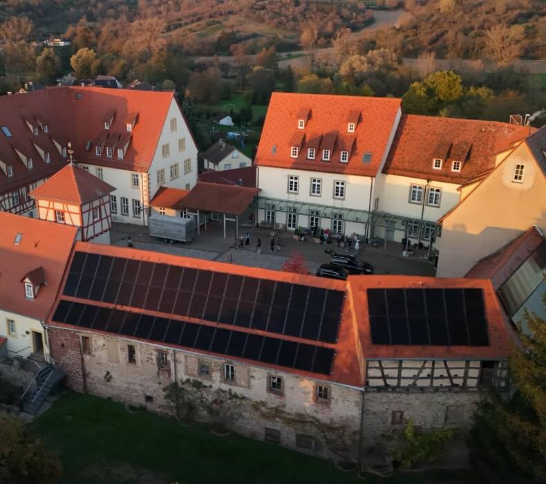 Drohnenaufnahme einer großen Photovoltaik-Anlage auf einem alten Gebäude