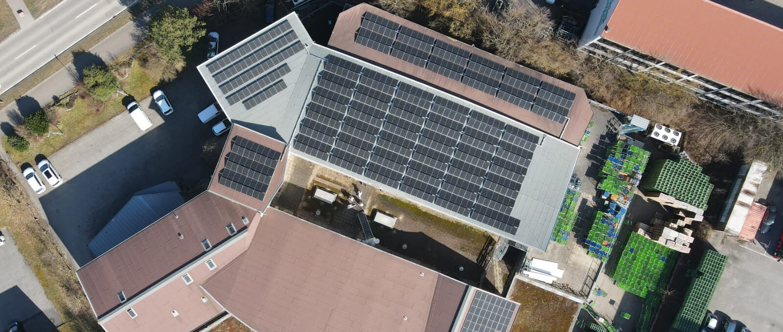 Kleinkind auf dem Arm eines Mannes vor einer PV-Anlage auf einem Hausdach im Hintergrund geht die Sonne unter.